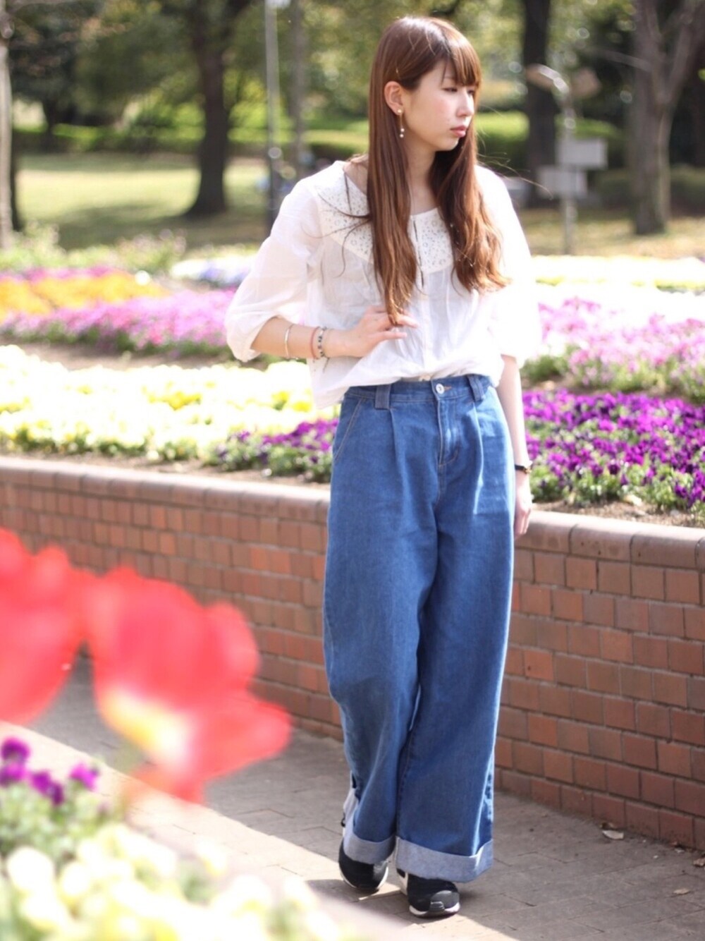 ブルー系のデニムパンツ、ブラック系のスニーカー、ブラック系のアナログ腕時計を着用したレディースの春コーディネートの1枚目の写真