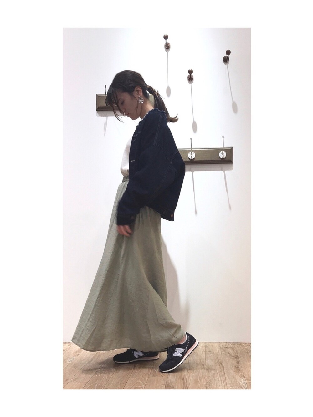 ブルー系のデニムジャケット、グリーン系のスカート、ホワイト系のニット/セーターを着用したレディースの秋コーディネートの1枚目の写真