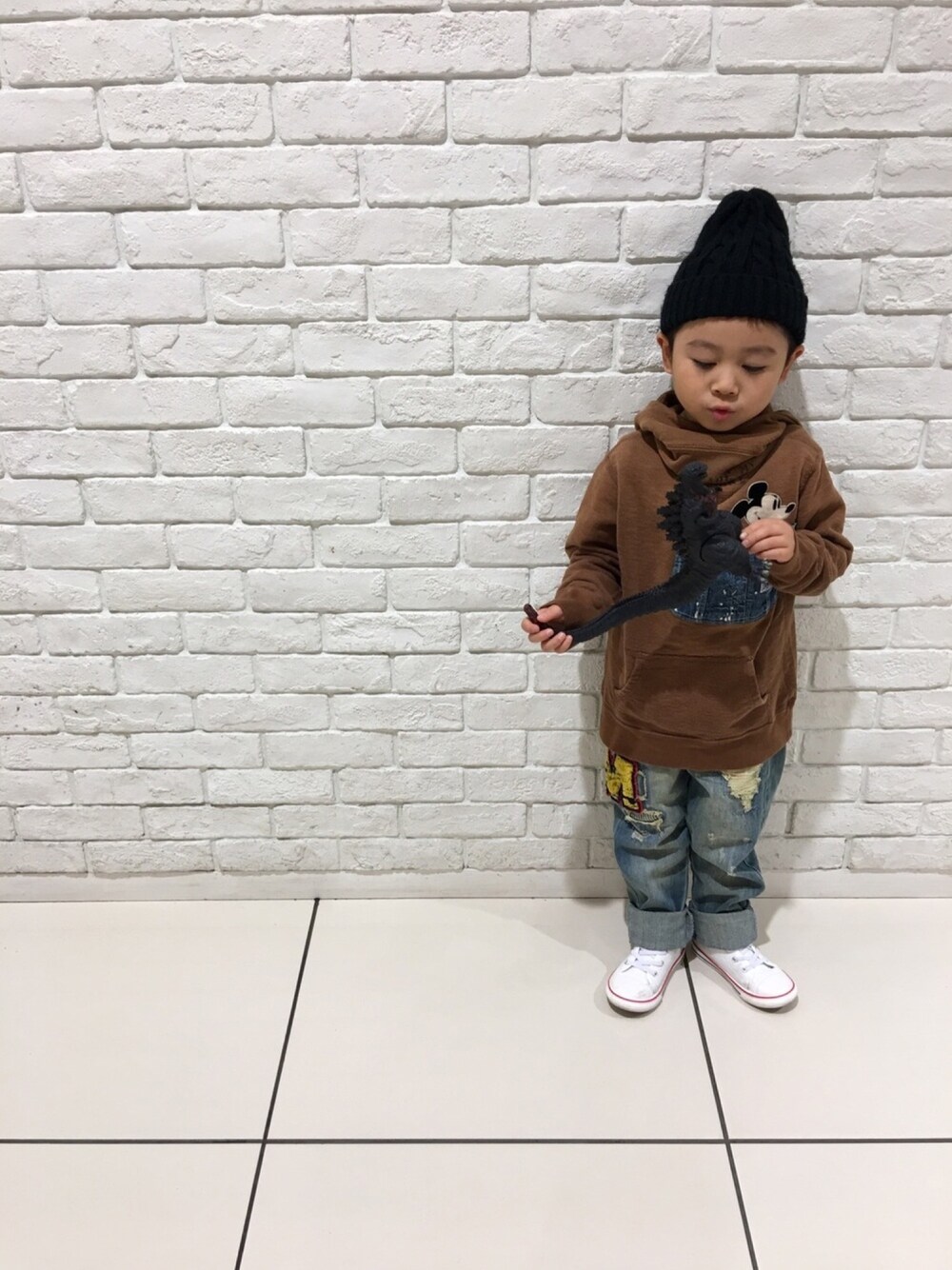 ブラウン系のパーカー、ブルー系のデニムパンツ、ホワイト系のスニーカーを着用したキッズの冬コーディネートの1枚目の写真