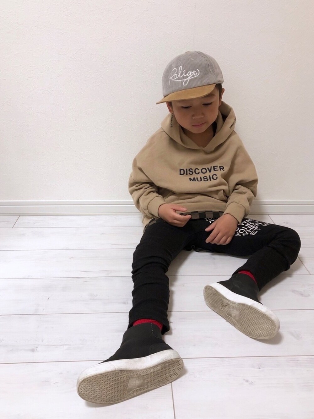 ブラック系のブルゾン、ベージュ系のパーカー、ブラック系のパンツを着用したキッズの冬コーディネートの1枚目の写真