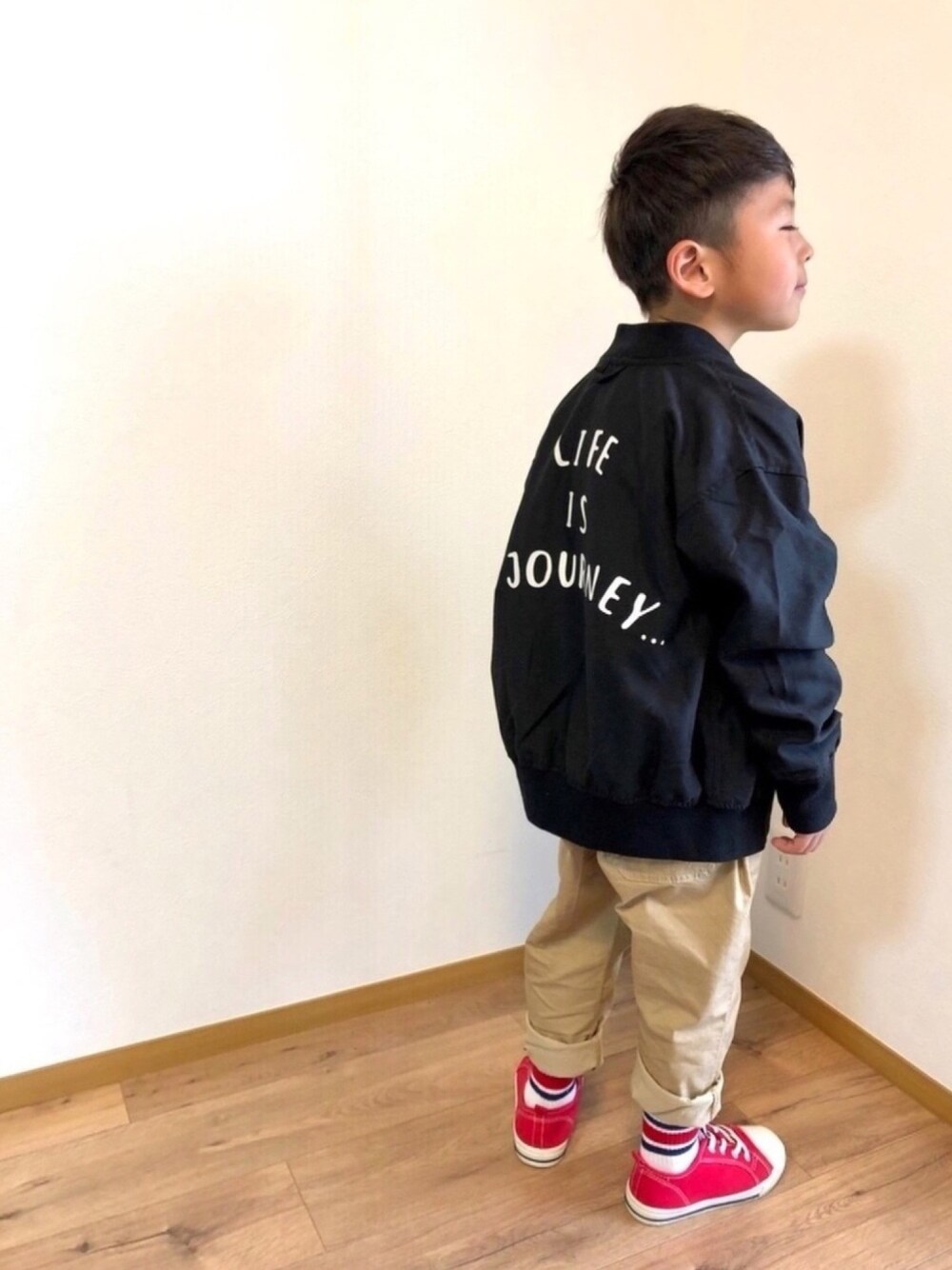 ブラック系のブルゾン、ホワイト系のTシャツ/カットソー、ベージュ系のパンツを着用したキッズの春コーディネートの1枚目の写真