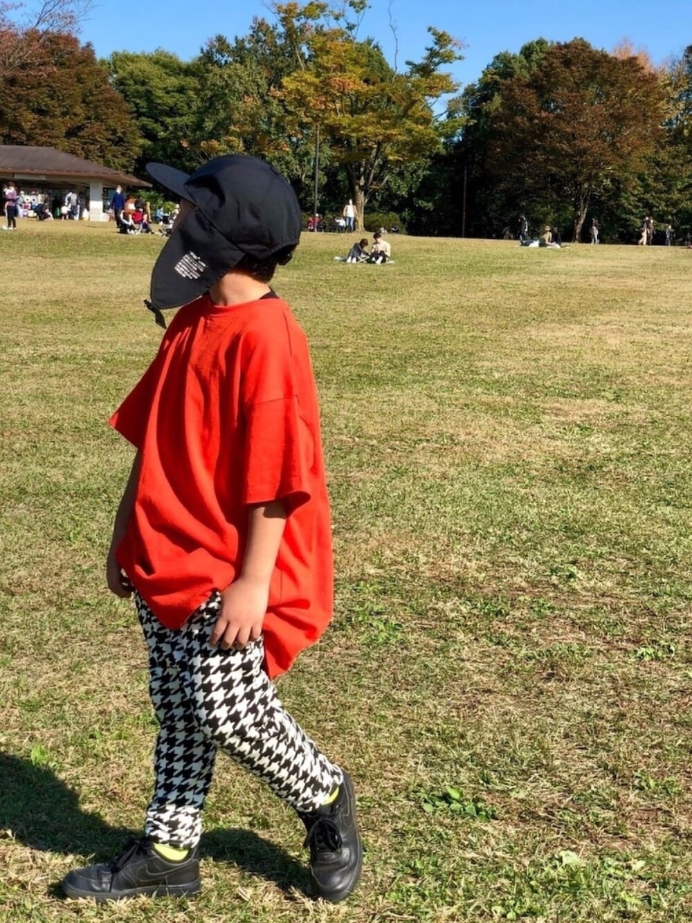 オレンジ系のTシャツ/カットソー、ホワイト系のその他パンツ、ブラック系のスニーカーを着用したキッズの秋コーディネートの1枚目の写真