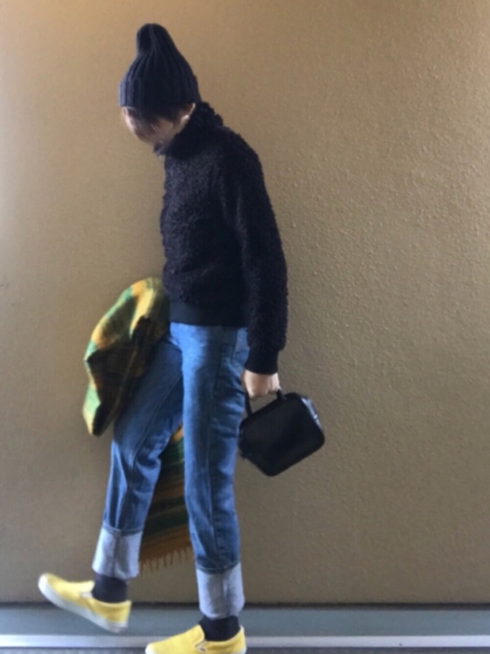ブラック系のブルゾン、ブルー系のデニムパンツ、イエロー系のスリッポンを着用したレディースの冬コーディネートの1枚目の写真
