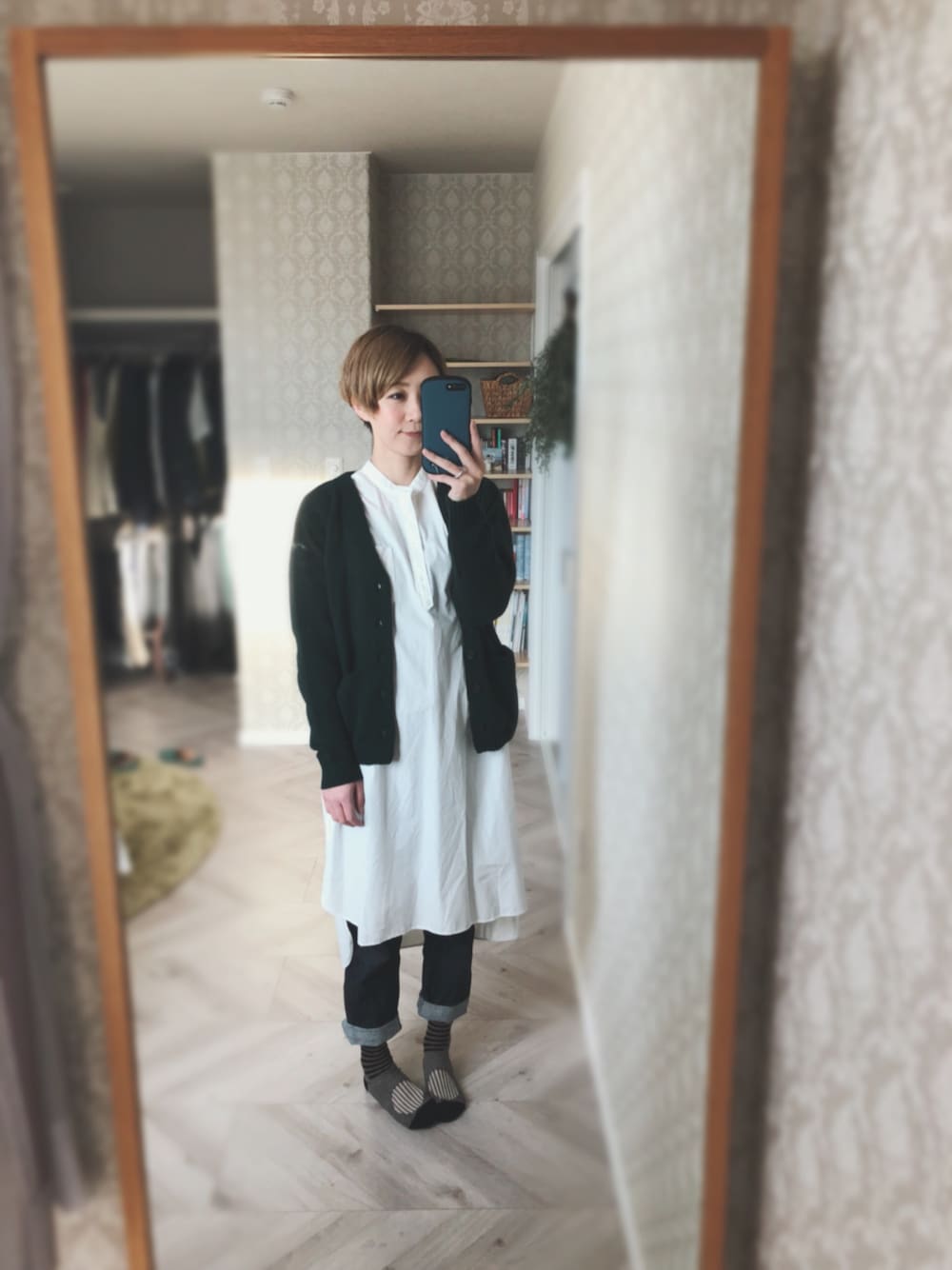 グリーン系のカーディガン/ボレロ、ホワイト系のワンピース、ブルー系のデニムパンツを着用したレディースの秋コーディネートの1枚目の写真