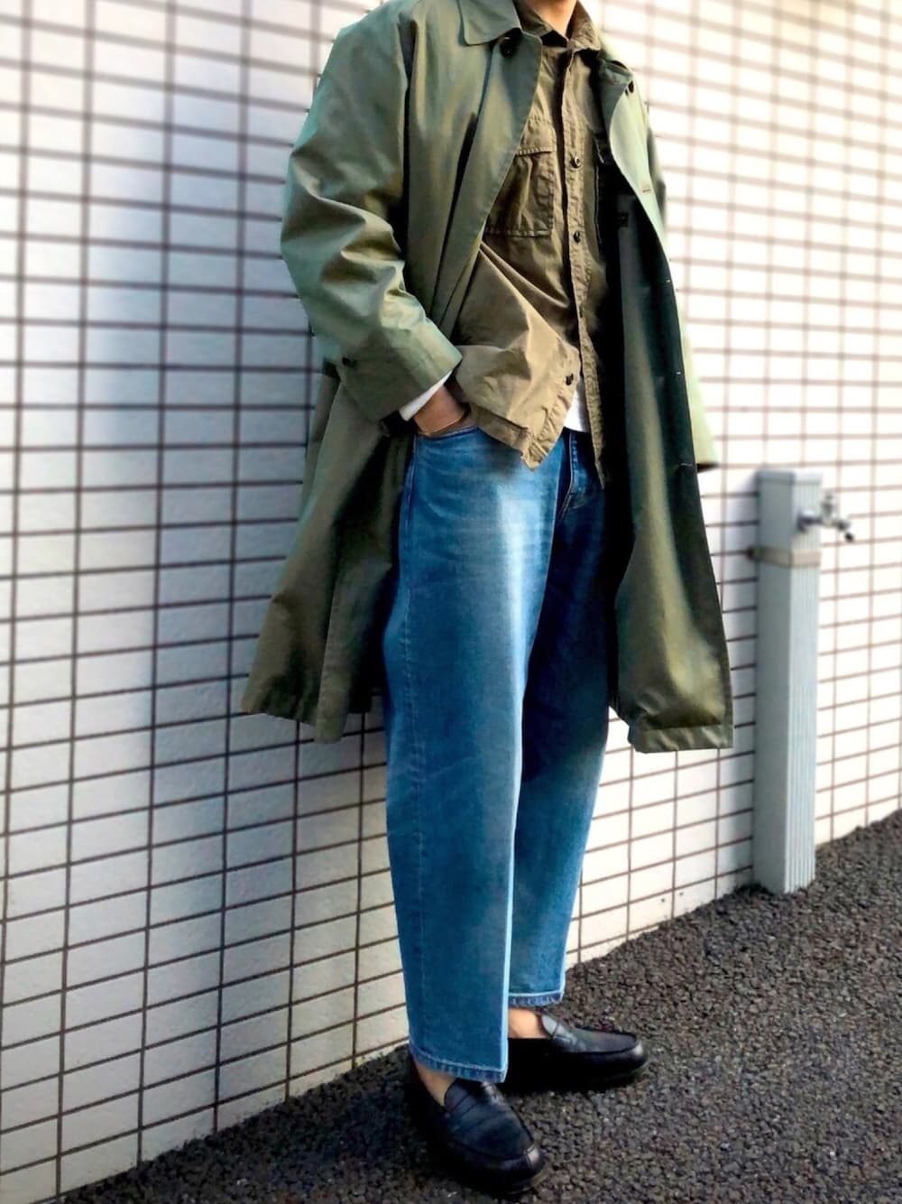 ブルー系のデニムパンツ、グリーン系のステンカラーコート、グリーン系のシャツ/ブラウスを着用したメンズの春コーディネートの1枚目の写真