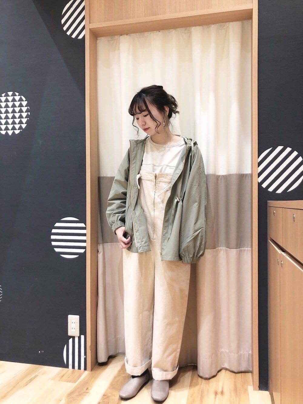 ホワイト系のデニムパンツ、グリーン系のマウンテンパーカー、ブラウン系のドレスシューズを着用したレディースの春コーディネートの1枚目の写真