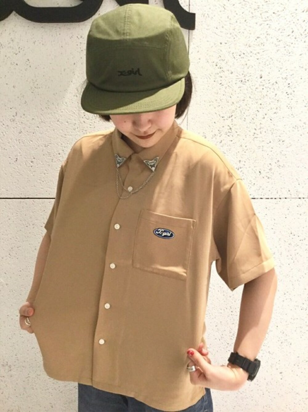 ベージュ系のシャツ/ブラウス、シルバー系のブローチ/コサージュ、グリーン系のキャップを着用したレディースの春コーディネートの1枚目の写真