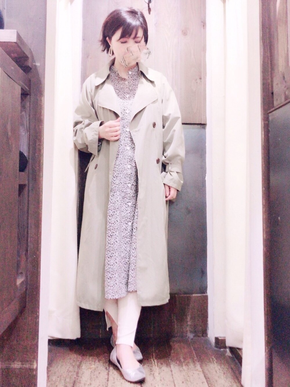 グリーン系のトレンチコート、グレー系のシャツワンピース、ベージュ系のレギンス/スパッツを着用したレディースの冬コーディネートの1枚目の写真