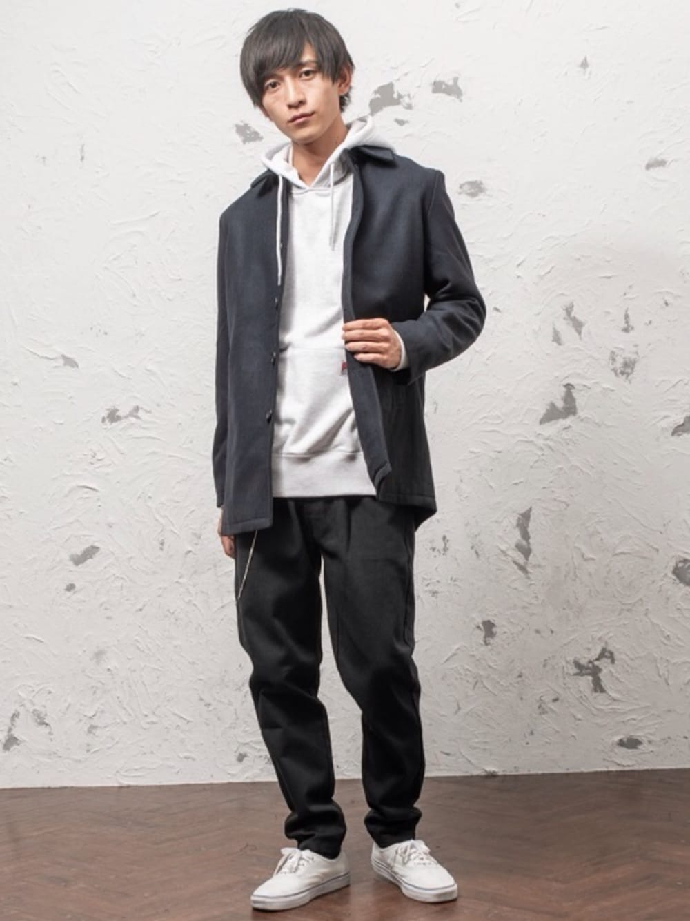 グレー系のステンカラーコート、ブラック系のパーカー、グレー系のチノパンツを着用したメンズの冬コーディネートの1枚目の写真