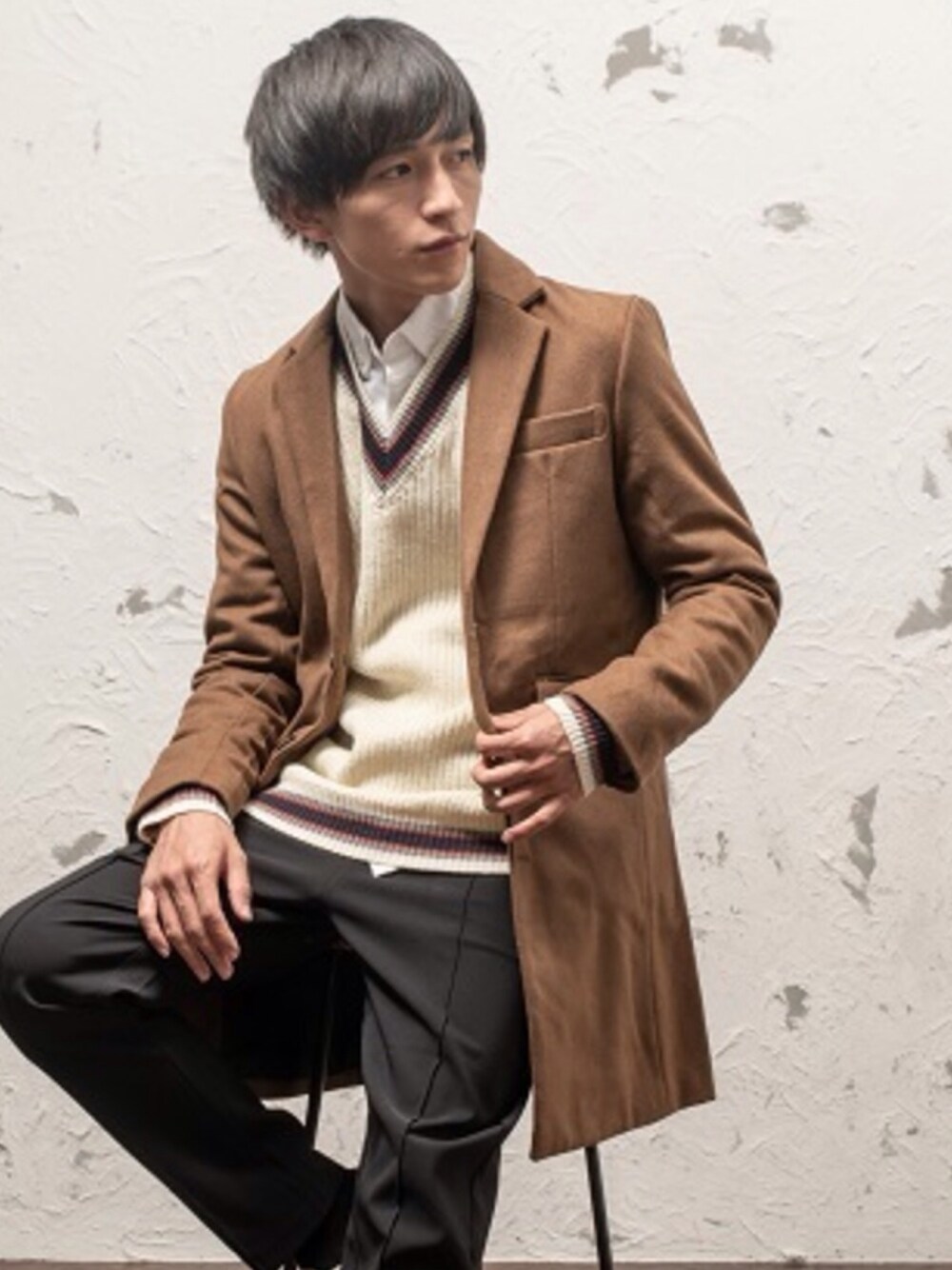 ブラック系のチェスターコート、ホワイト系のニット/セーター、ブラウン系のその他パンツを着用したメンズの冬コーディネートの1枚目の写真