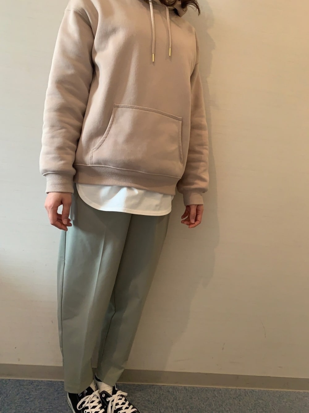 ベージュ系のパーカー、グリーン系のスラックス、ホワイト系のTシャツ/カットソーを着用したレディースの冬コーディネートの1枚目の写真