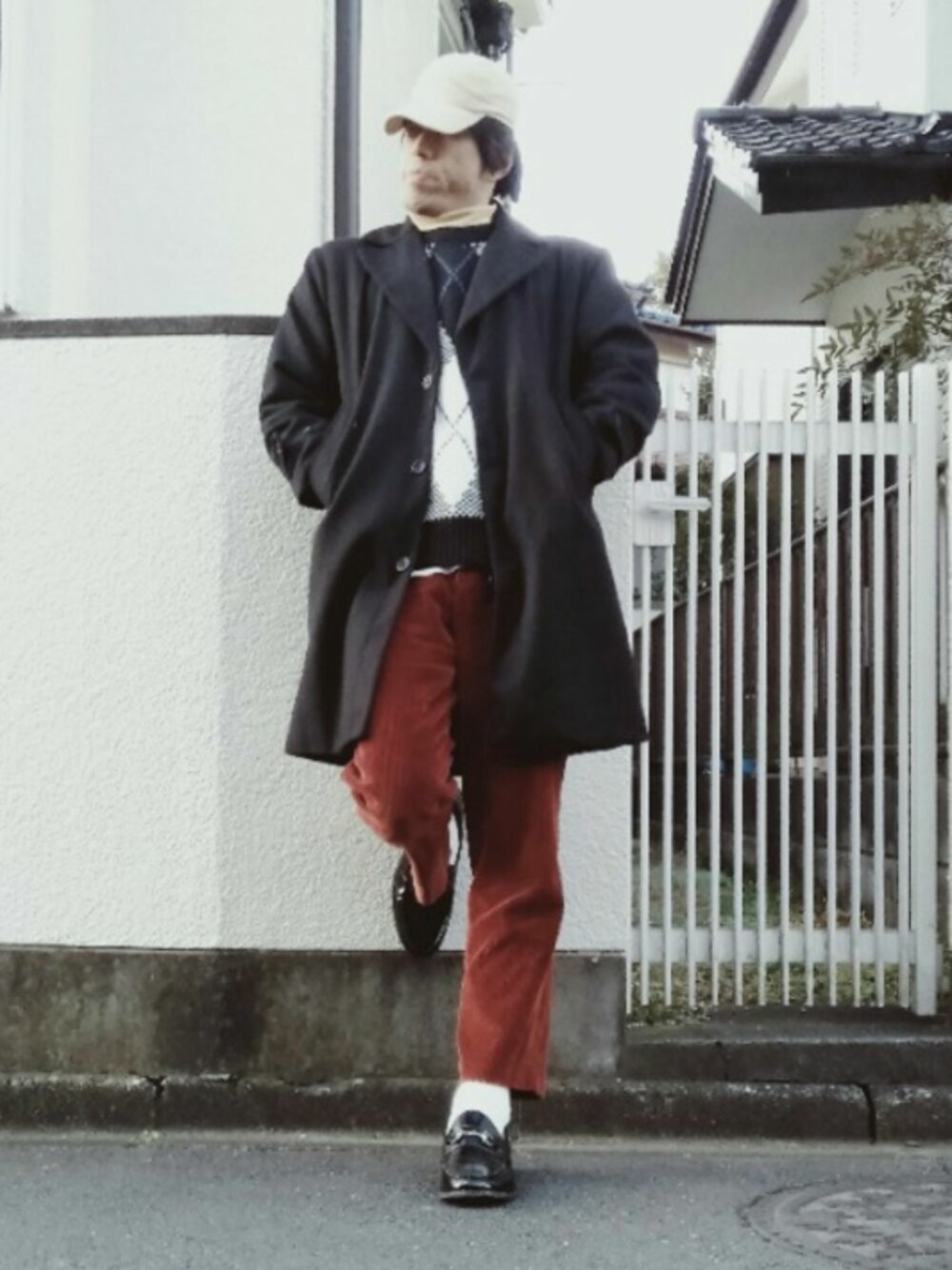 ブラック系のチェスターコート、ブラック系のニット/セーター、ブラウン系のその他パンツを着用したメンズの冬コーディネートの1枚目の写真