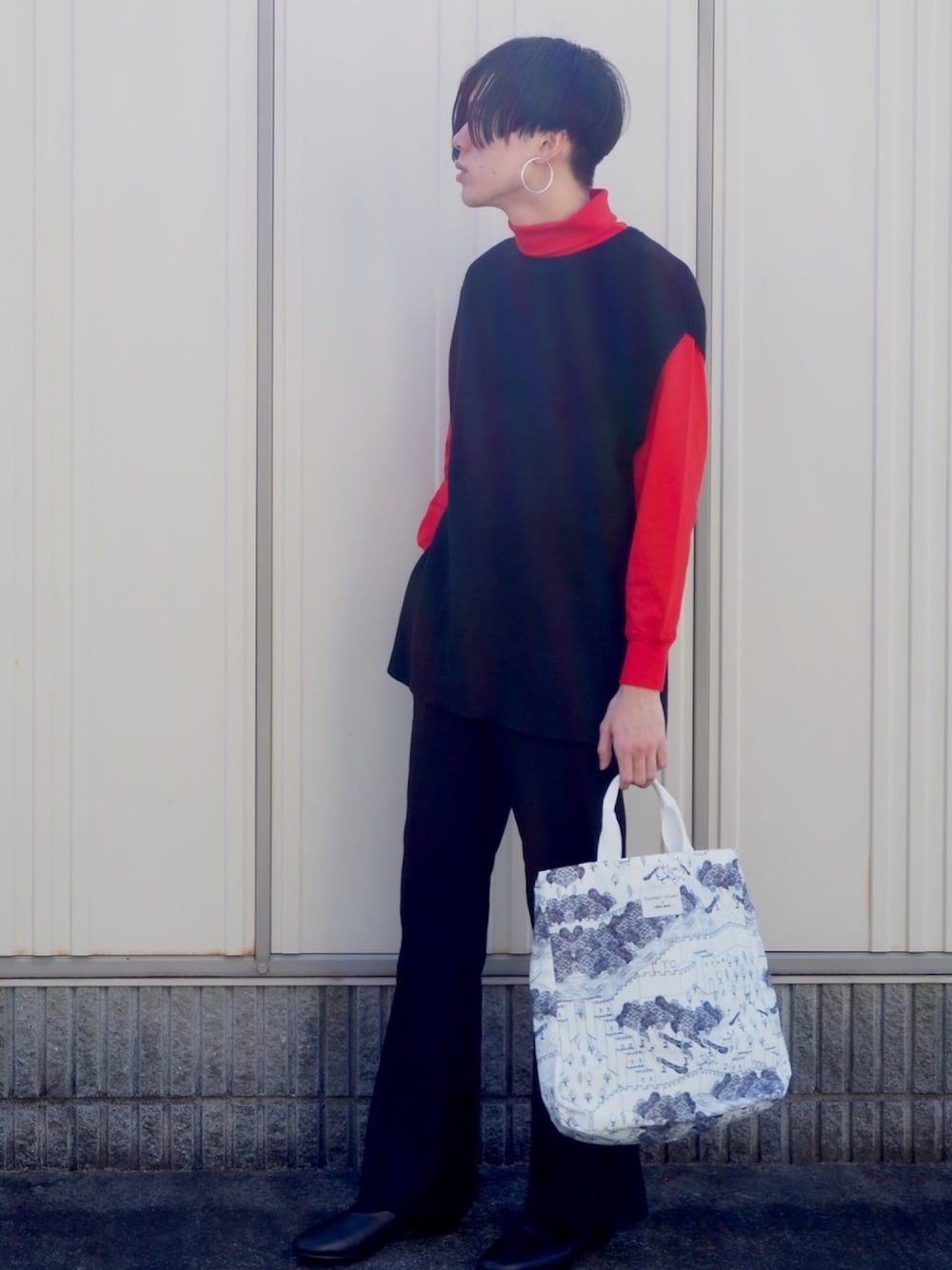 オレンジ系のTシャツ/カットソー、ブラック系のニット/セーター、ブラック系のスラックスを着用したメンズの冬コーディネートの1枚目の写真