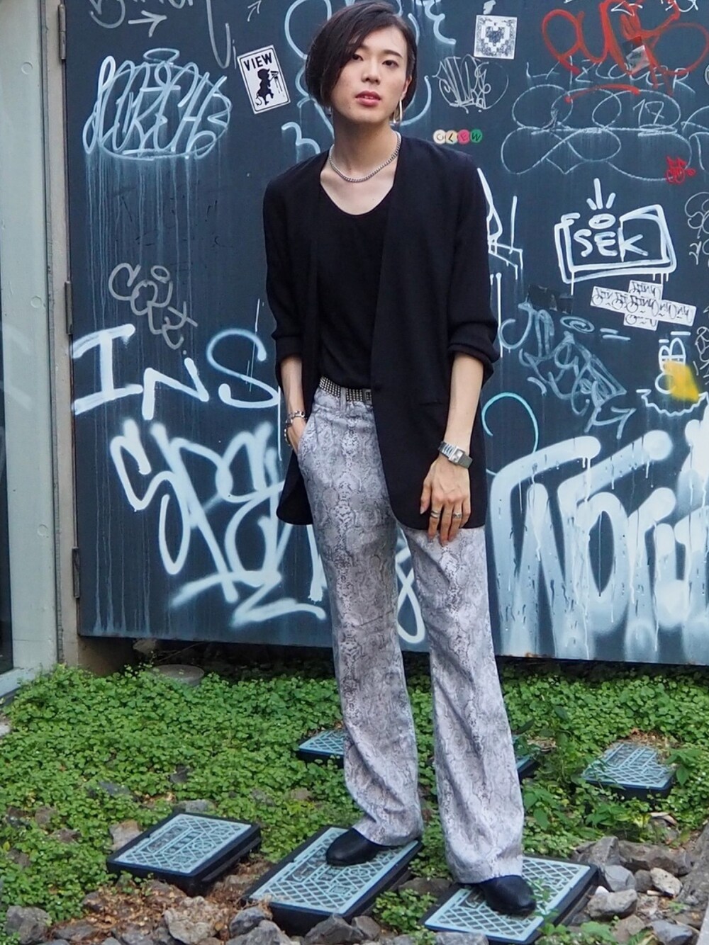 ブラック系のノーカラージャケット、グレー系のスラックス、ブラック系のスリッポンを着用したメンズの夏コーディネートの1枚目の写真