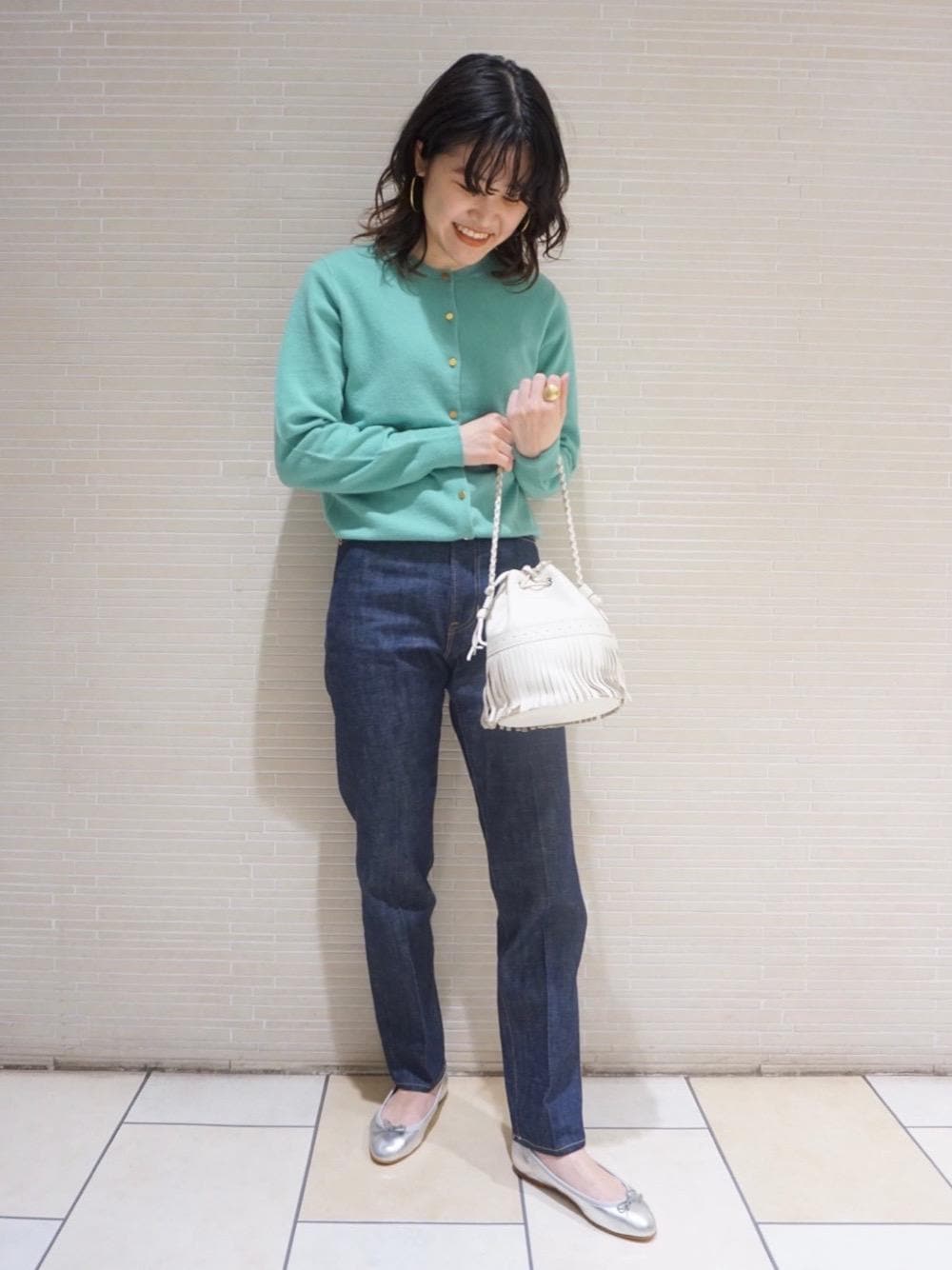 シルバー系のバレエシューズ、ブルー系のデニムパンツ、グリーン系のカーディガン/ボレロを着用したレディースの冬コーディネートの1枚目の写真
