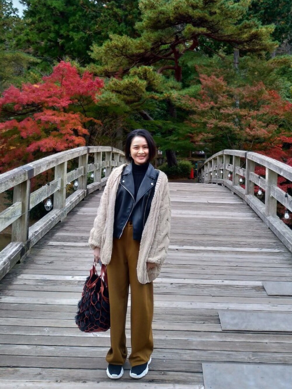 イエロー系のカーディガン/ボレロ、ブラック系のライダースジャケット、ブラウン系のその他パンツを着用したレディースの秋コーディネートの1枚目の写真