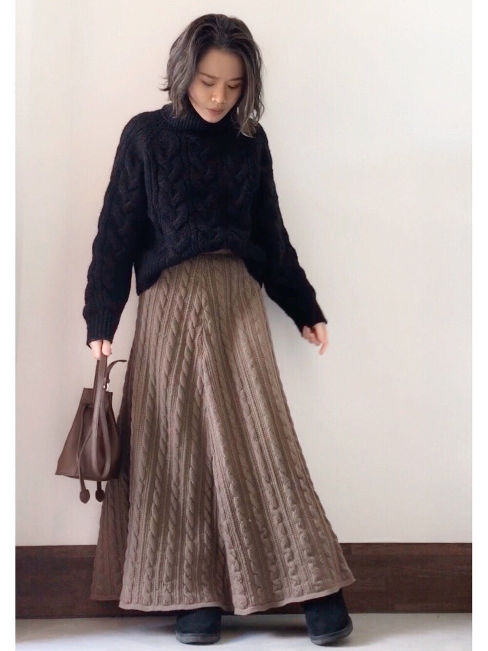 ブラック系のニット/セーター、ブラウン系のスカート、ブラウン系のショルダーバッグを着用したレディースの冬コーディネートの1枚目の写真