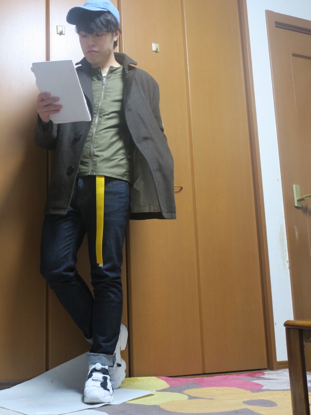 ホワイト系のスニーカー、ブルー系のデニムパンツ、グリーン系のミリタリージャケットを着用したメンズの冬コーディネートの1枚目の写真
