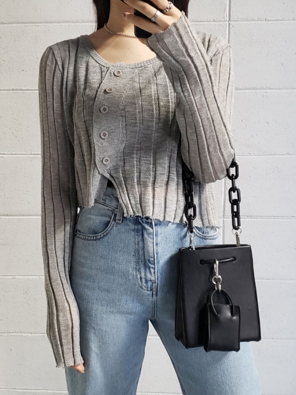 グレー系のカーディガン/ボレロ、ブラック系のショルダーバッグ、ブルー系のデニムパンツを着用したレディースの春コーディネートの1枚目の写真