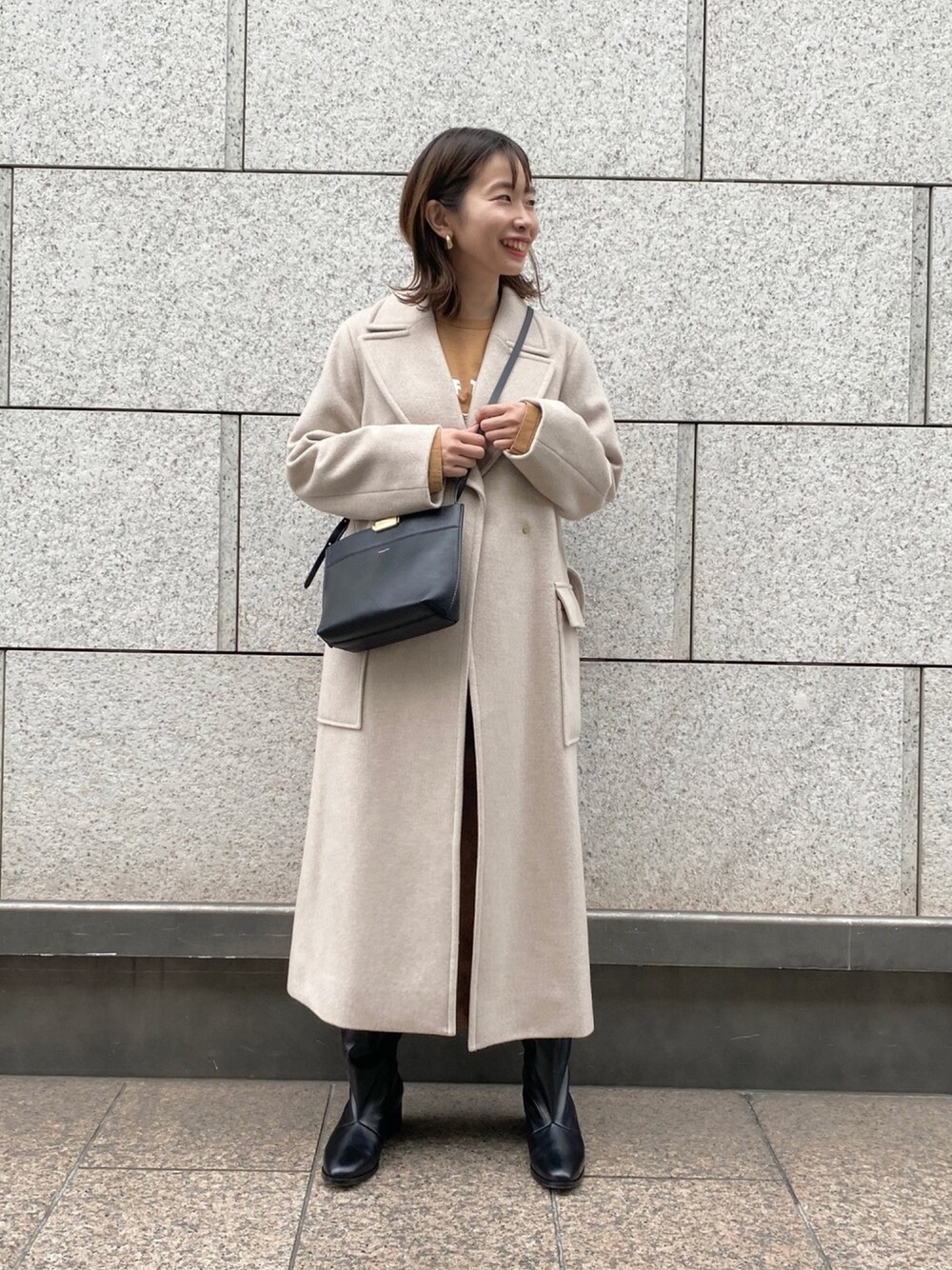 ベージュ系のその他アウター、ブラック系のショルダーバッグ、ブラック系のブーツを着用したレディースの冬コーディネートの1枚目の写真