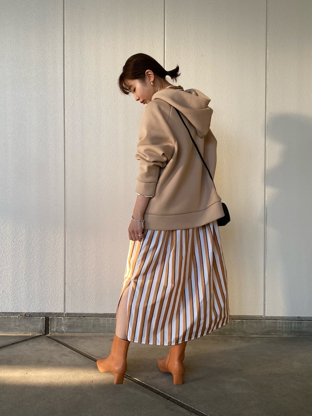 ベージュ系のスウェット、ベージュ系のシャツワンピース、オレンジ系のブーツを着用したレディースの冬コーディネートの1枚目の写真