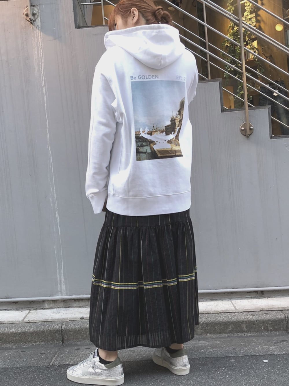 ホワイト系のパーカー、ブラック系のスカート、シルバー系のスニーカーを着用したレディースの春コーディネートの1枚目の写真
