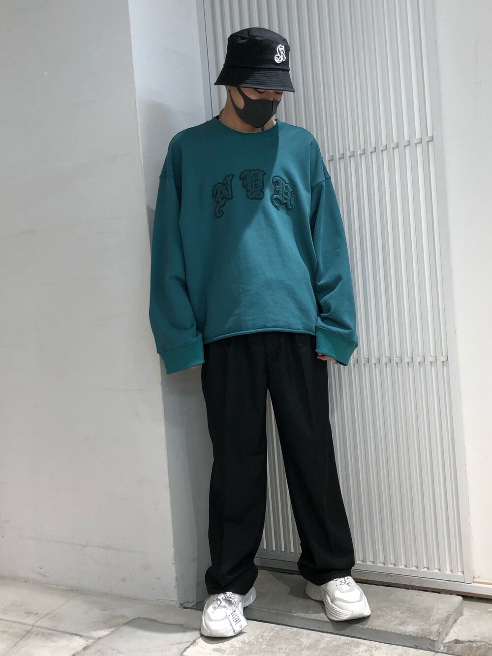 グリーン系のスウェット、ブラック系のスラックス、ホワイト系のスニーカーを着用したメンズの冬コーディネートの1枚目の写真