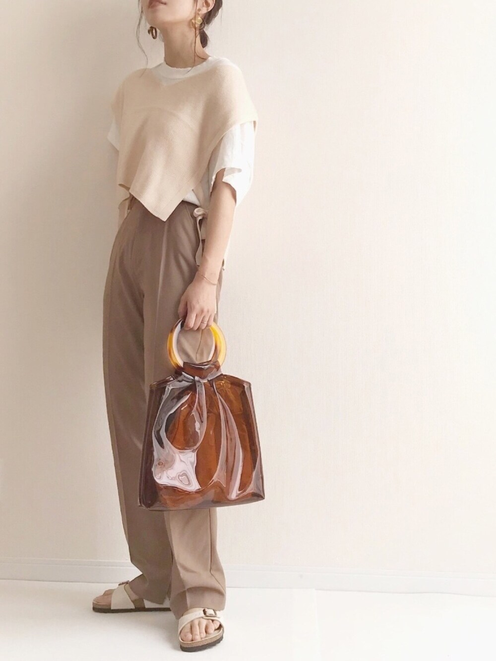 ホワイト系のベスト、ホワイト系のTシャツ/カットソー、ベージュ系のスラックスを着用したレディースの夏コーディネートの1枚目の写真