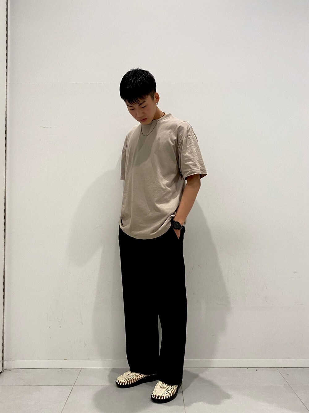 ベージュ系のTシャツ/カットソー、ホワイト系のサンダル、ブラック系のスラックスを着用したメンズの夏コーディネートの1枚目の写真