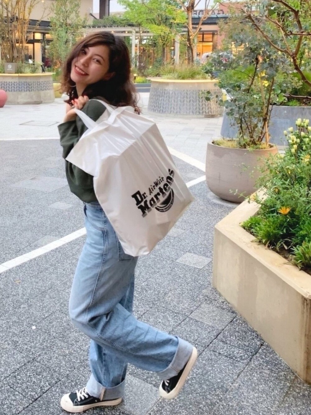 グリーン系のTシャツ/カットソー、ブルー系のデニムパンツ、ブラック系のスニーカーを着用したレディースの春コーディネートの1枚目の写真