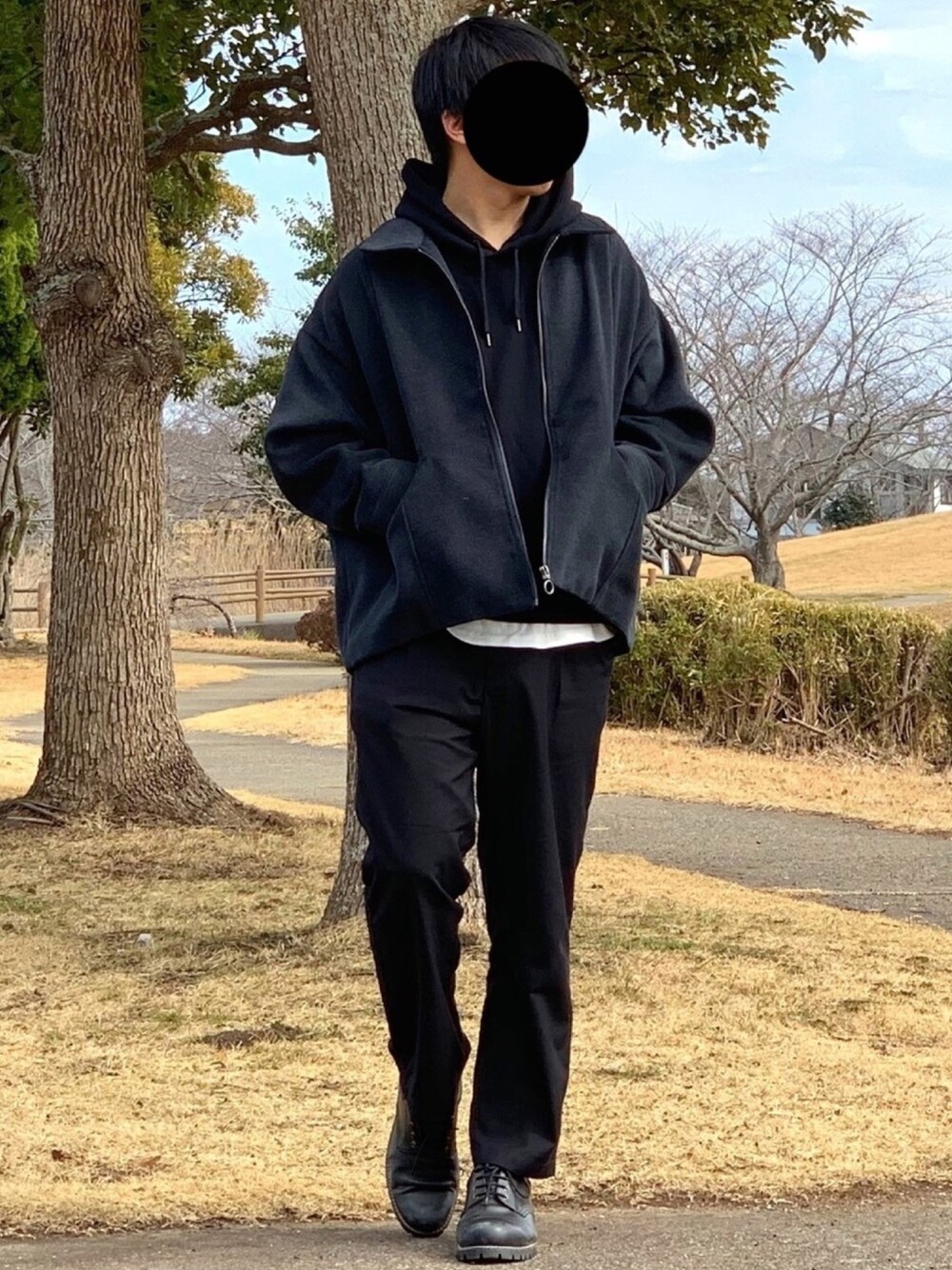 グレー系のブルゾン、ブラック系のパーカー、ホワイト系のタンクトップを着用したメンズの冬コーディネートの1枚目の写真