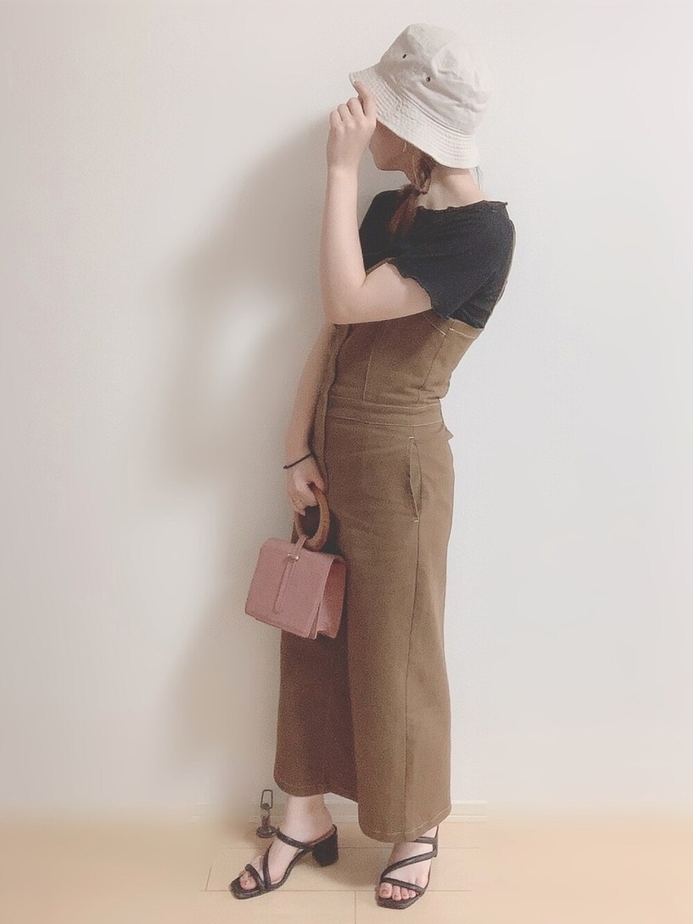 ブラウン系のジャンパースカート、ピンク系のハンドバッグ、ブラック系のトップスを着用したレディースの秋コーディネートの1枚目の写真